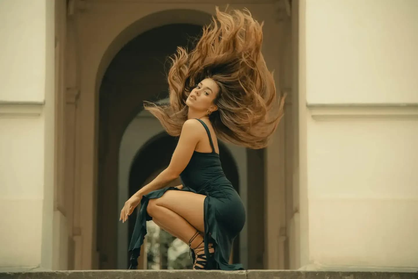 Porträt einer Frau mit fließenden braunen Haaren in eleganter dunkler Kleidung vor einer modernen Architektur, professionelle