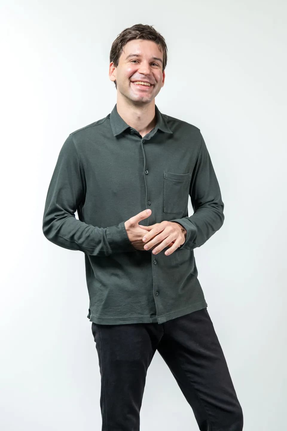 Freundlich lachender Mitarbeiter im gruenen Hemd vor weissem Studiohintergrund, Firmenfotograf Wien