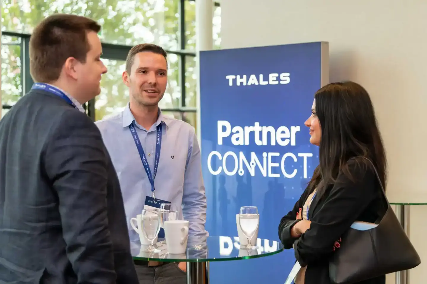 Drei Geschäftsleute im Gespräch bei der Thales Partner Connect Veranstaltung in Wien - professionelle Eventfotografie