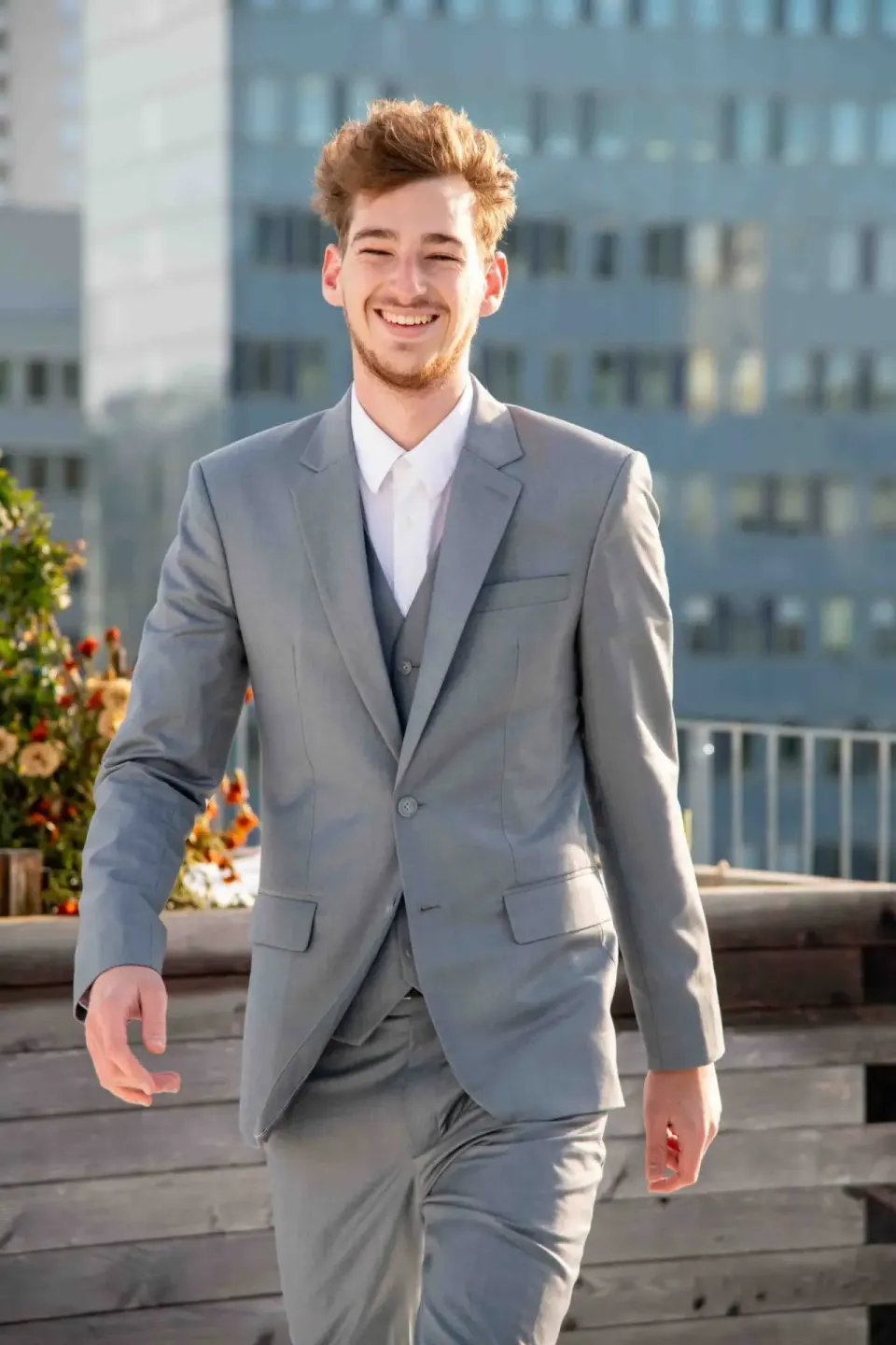 Junger Mann im grauen Business-Anzug auf einer Dachterrasse mit Wiener Skyline im Hintergrund - Headshots Wien