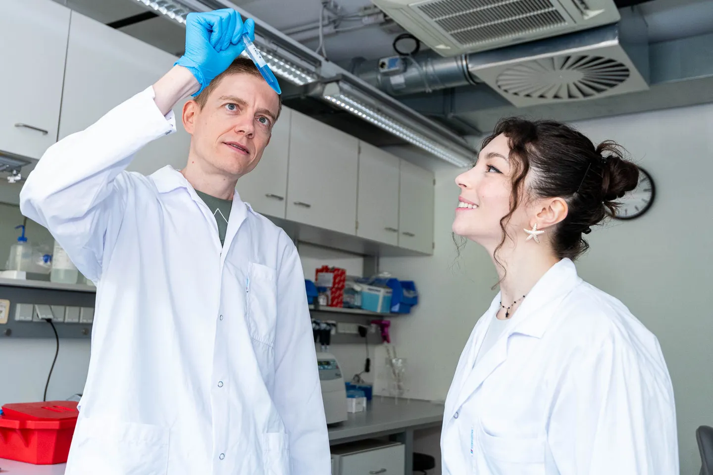 Forscher begutachtet ein Reagenzglas im Biotech-Labor aufmerksam, Firmenfotograf Wien
