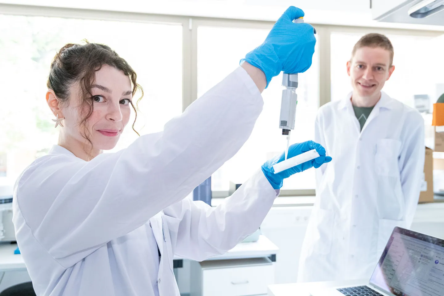 Forscherin mit Pipette blickt in die Kamera im Labor, Business Fotograf Wien