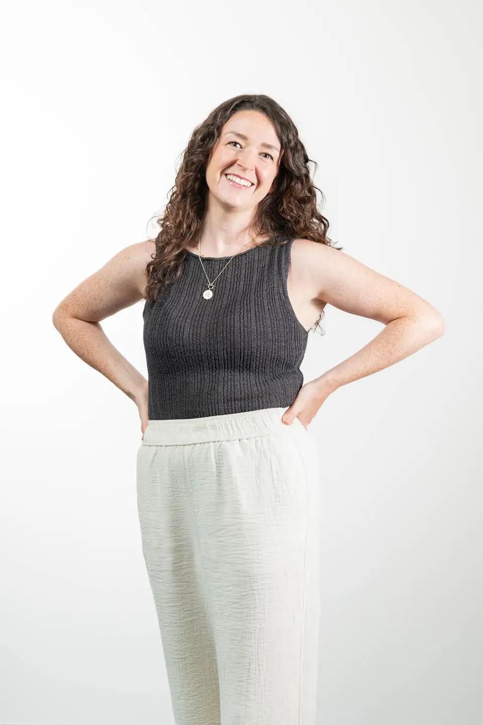 Frau mit Locken und Haenden an den Hueften posiert im Corporate Headshot, Wien