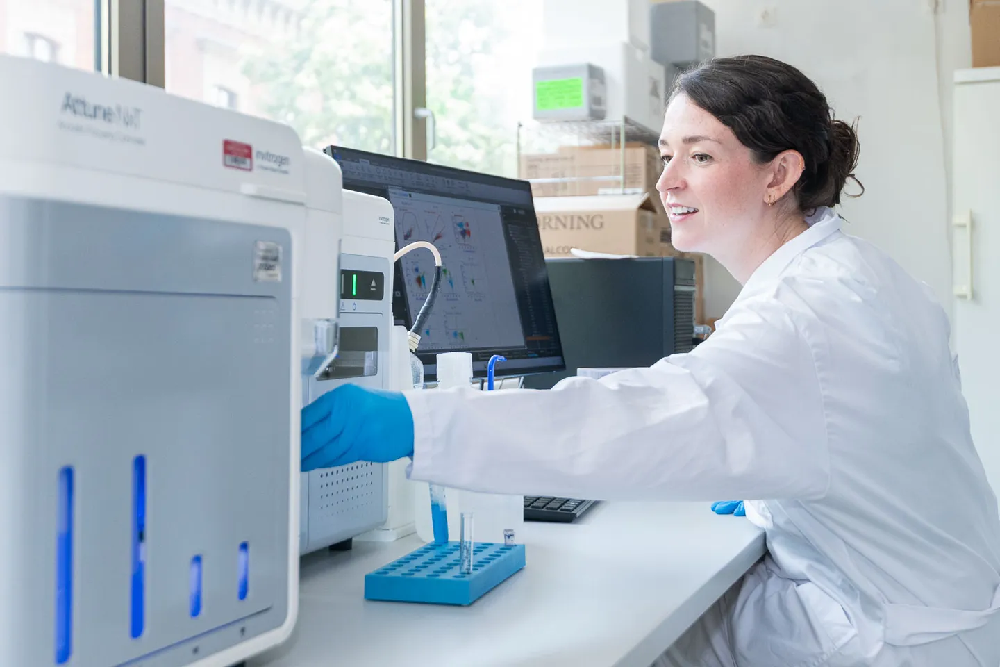 Labormitarbeiterin am Analysegeraet mit Monitor im Forschungslabor, Firmenfotografie Wien