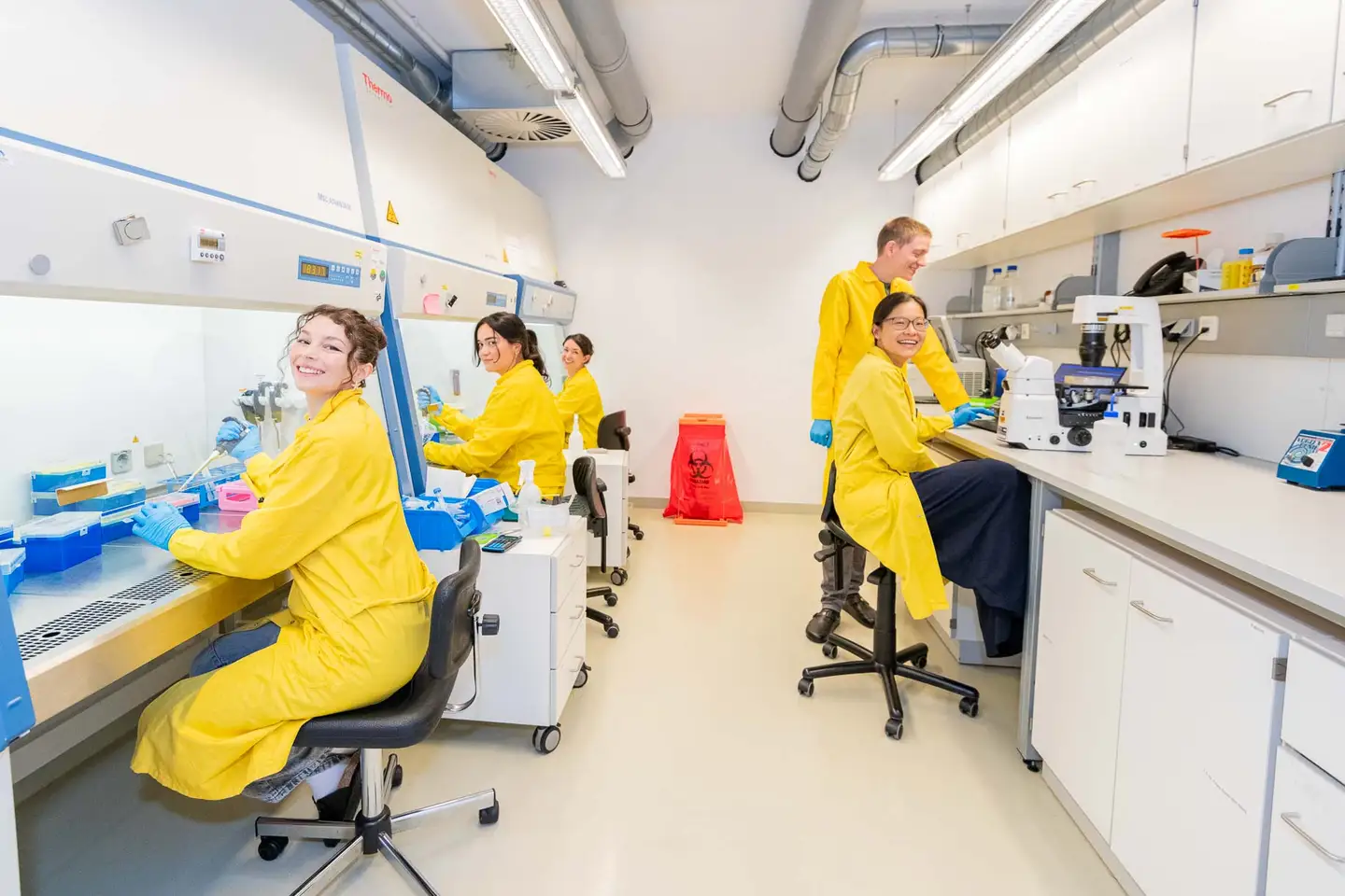 Lachendes Laborteam im Gruppenbild mit Kitteln bei ParallelBio, Teamfotografie Wien
