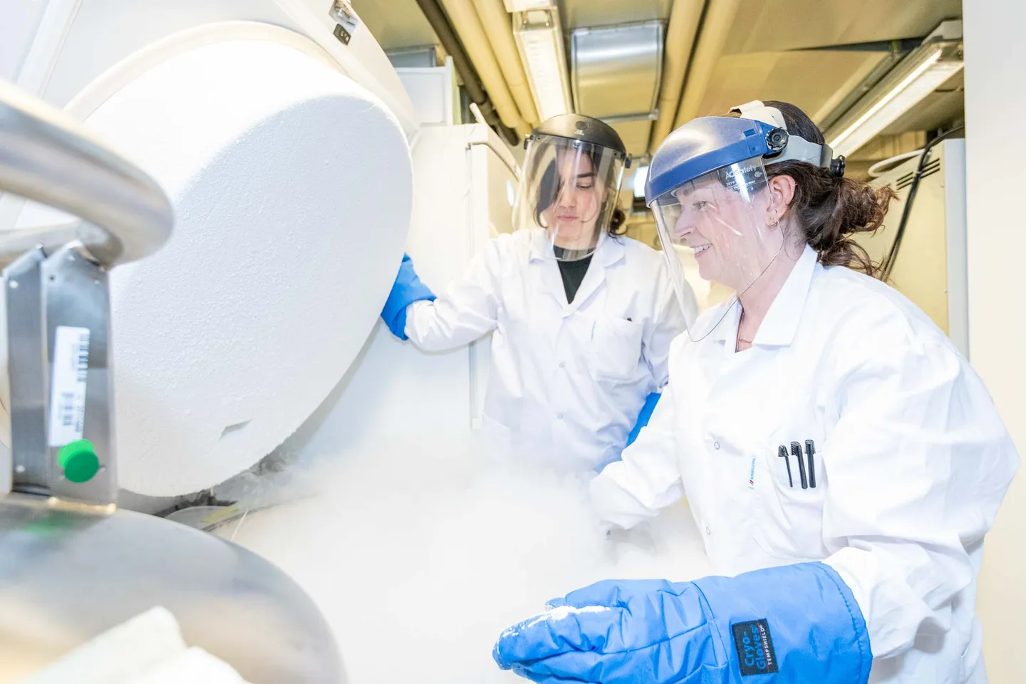 Lachendes Laborteam am Stickstofftank mit Dampfwolke im Kryolabor, Teamfotografie Wien