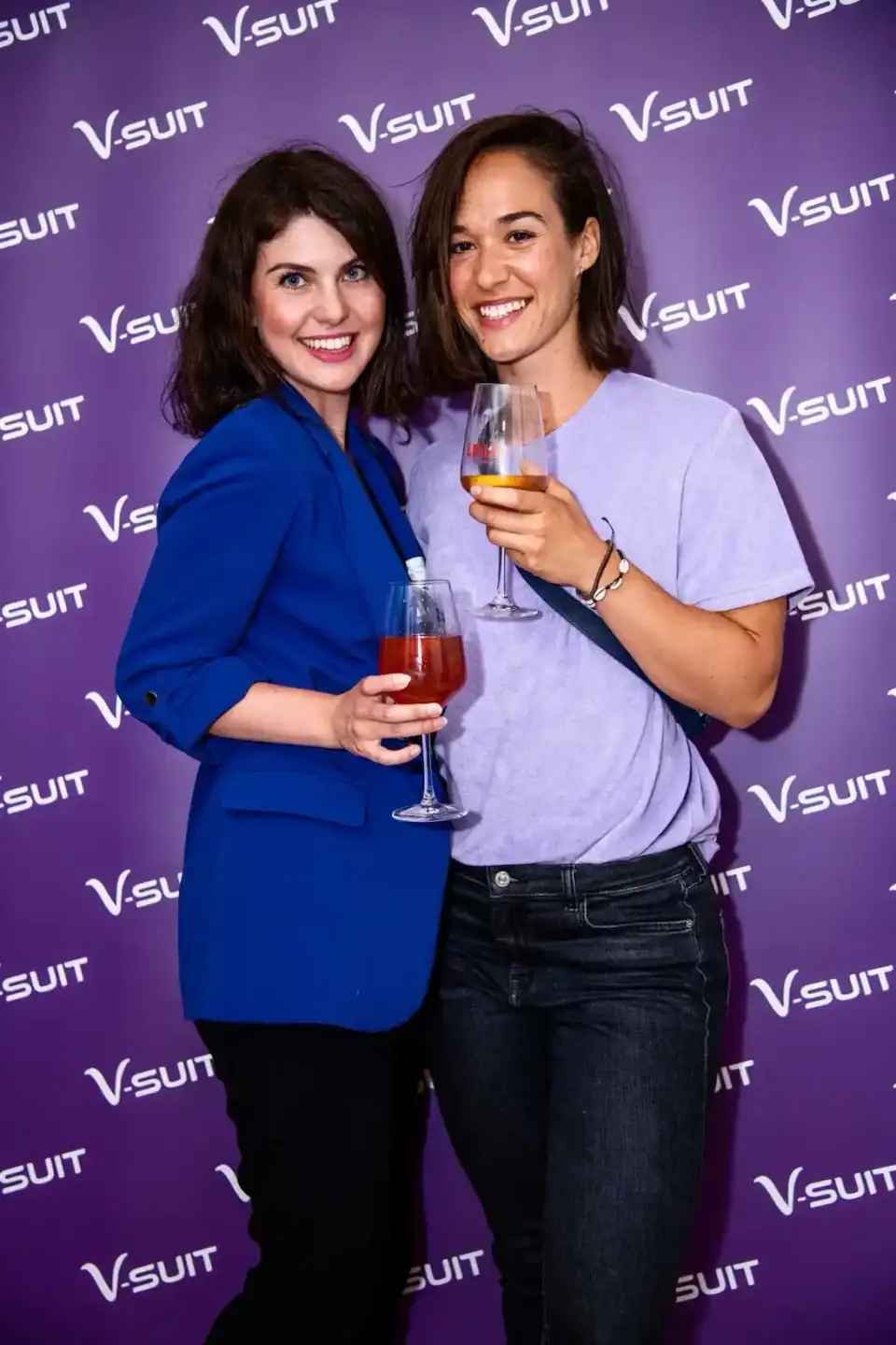 Zwei Frauen in eleganten Outfits stoßen mit Getränken an – professionelle Eventfotografie Wien