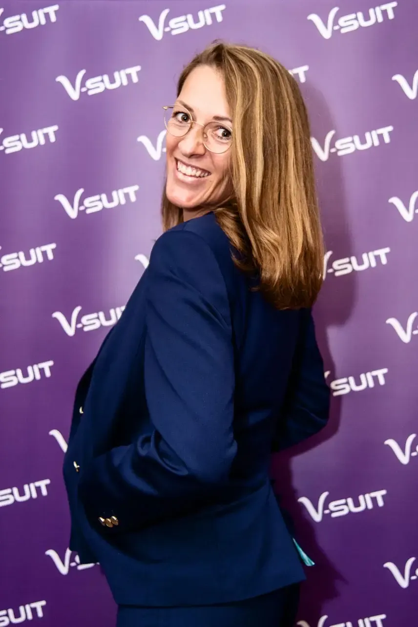 Lächelnde Frau in dunklem Blazer vor violettem V-suit Hintergrund – professionelle Eventfotografie Wien