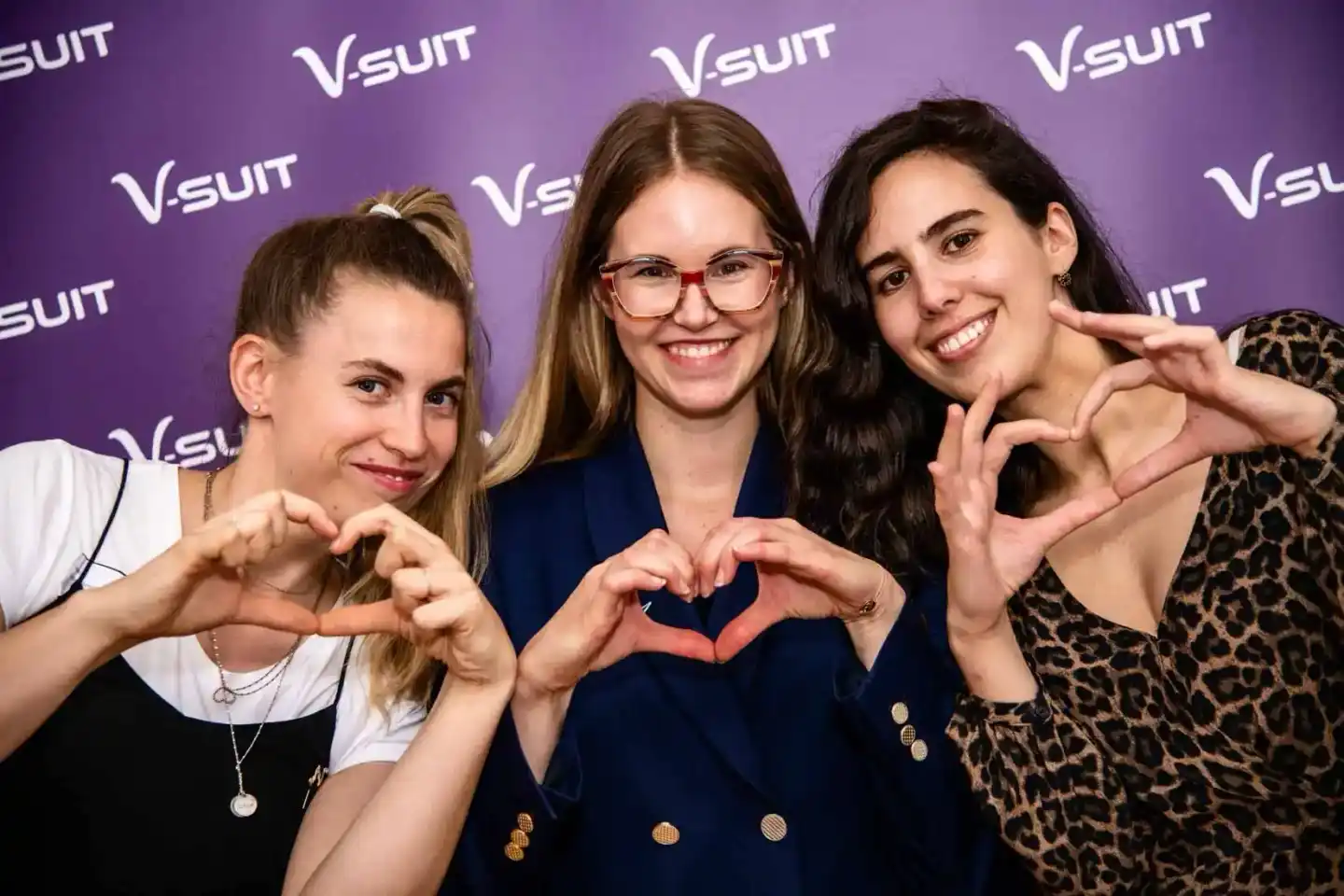 Drei Frauen machen Herzgesten vor der Vsuit-Bühne bei einem Eventfotografie Wien Auftritt