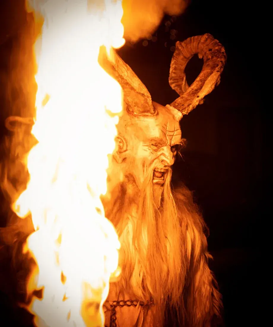 Brennende Krampus-Figur mit Hörnern und Bart bei Eventfotografie Wien, umgeben von Flammen gegen schwarzen Hintergrund
