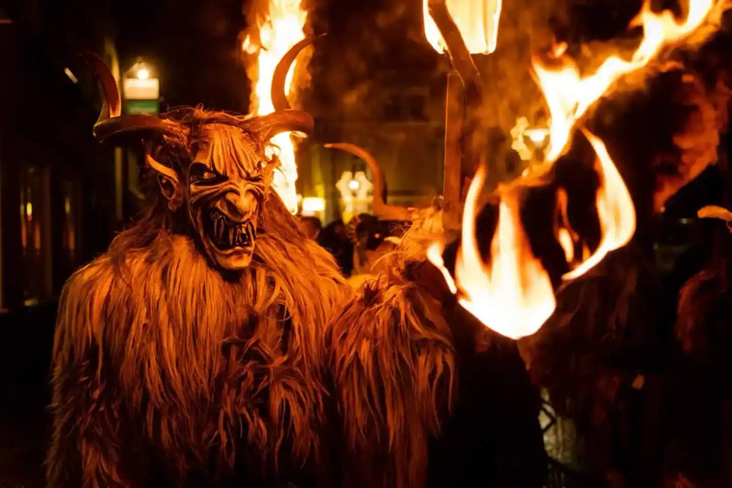 Krampus-Figur mit Hörnern und Pelz bei Nachtveranstaltung mit Feuer, professionelle Eventfotografie Wien