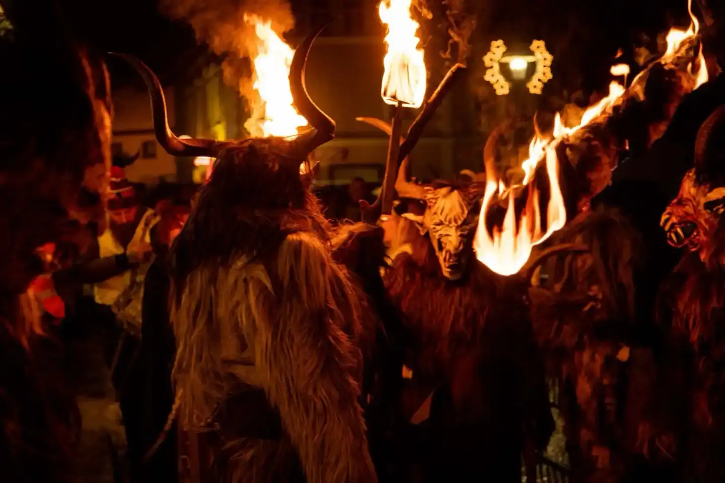 Krampus-Umzug in Wien: Personen in traditionellen Krampus-Kostümen mit brennenden Fackeln bei Veranstaltungsfotografie