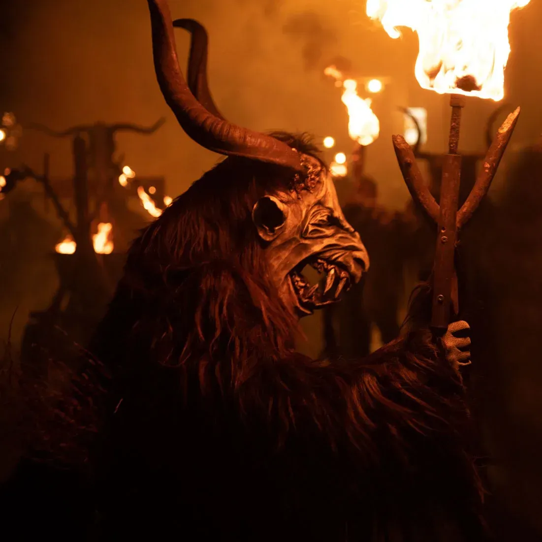 Krampus-Figur mit langen Hörnern und Trident bei Nachtfeuer, professionelle Eventfotografie Wien