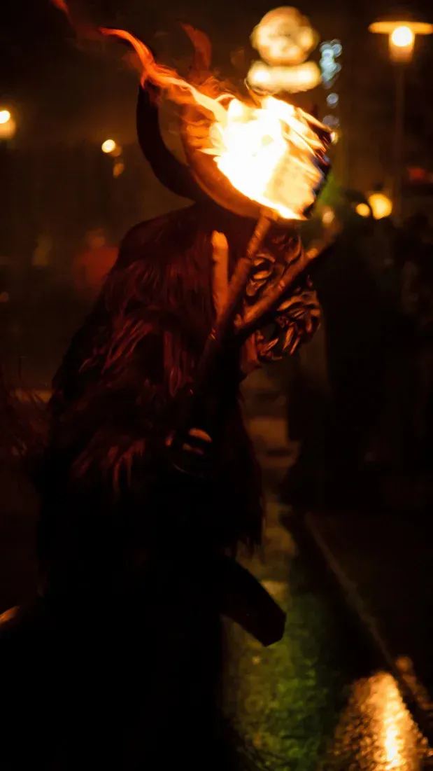 Krampus-Performer mit brennender Fackel bei Veranstaltungsfotografie Wien, dramatische Nachtaufnahme mit Feuer und Kostüm