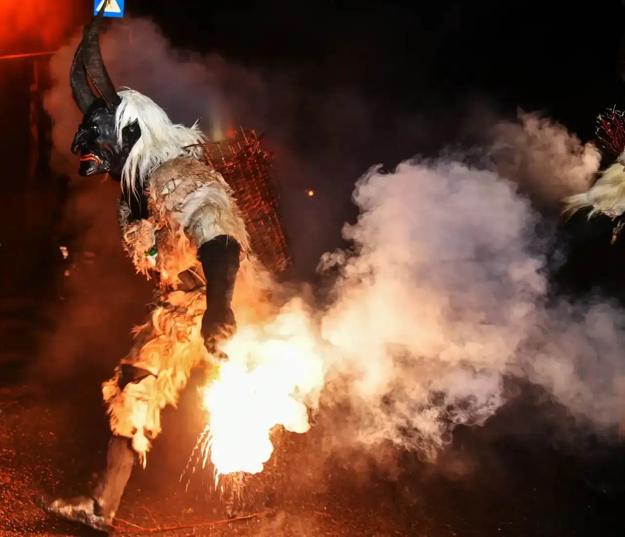 Krampus-Figur mit weißem Haar und großen Hörnern beim Feuershow-Performance auf dunkler Bühne - Eventfotografie Wien