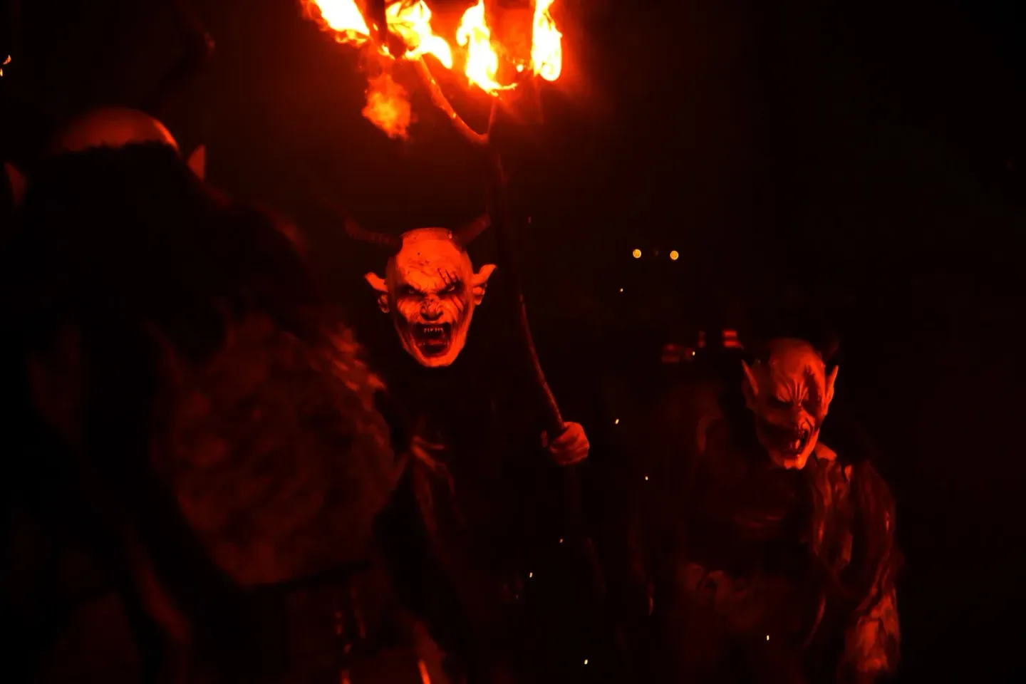 Krampus-Performer mit rot illuminiertem Dämonenkostüm und brennendem Feuer im Hintergrund bei Wiener Eventfotografie