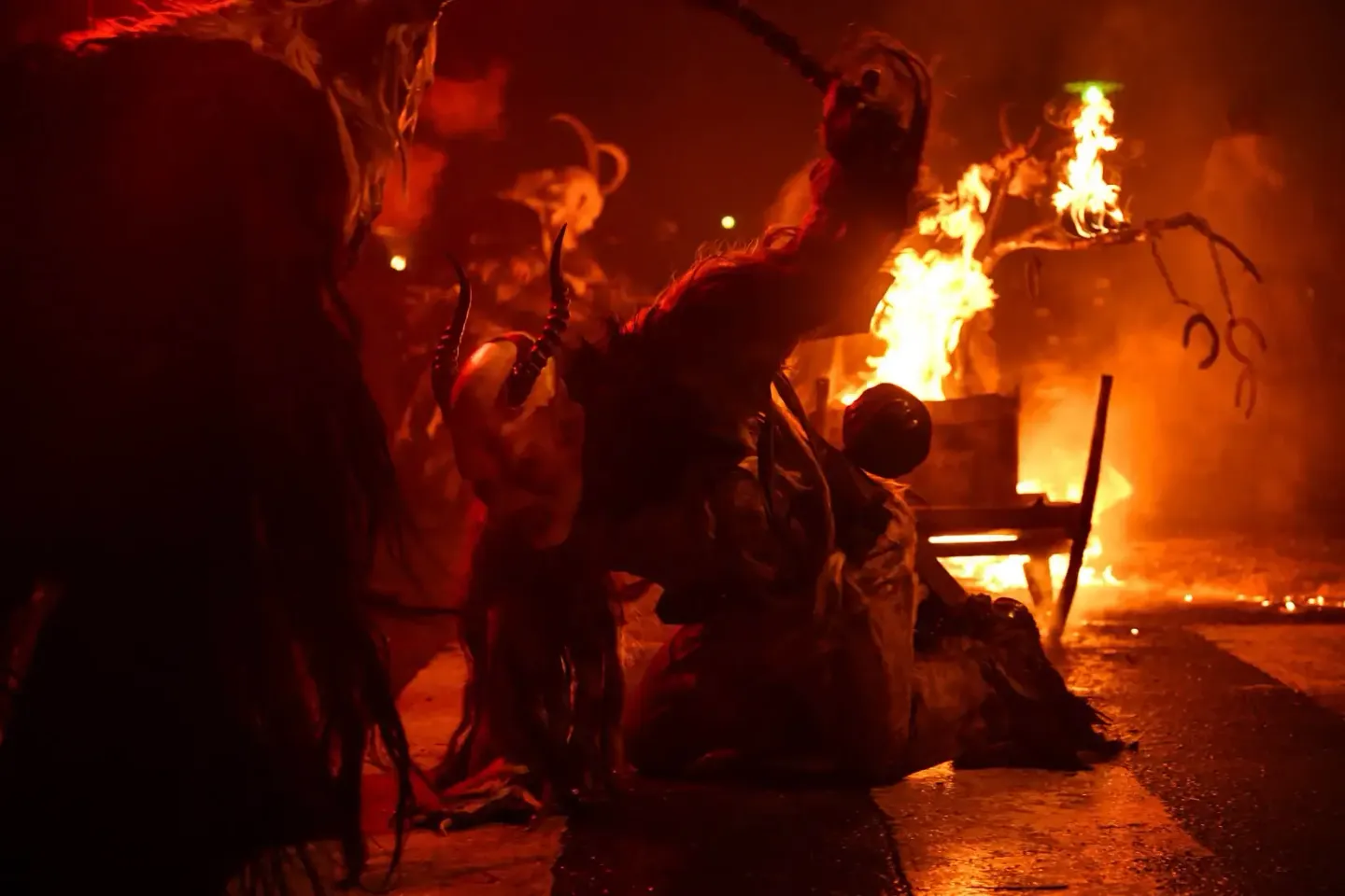 Krampus-Feuer bei Nacht: Performer in traditionellen Kostümen tanzen um brennende Fässer bei dieser spektakulären Veranstaltu