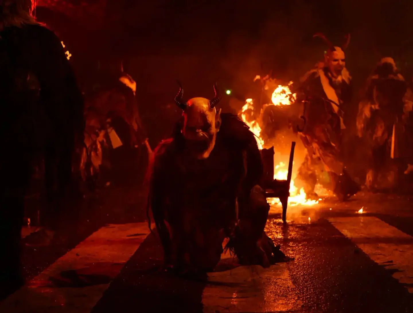 Krampus-Figur mit Hörnern bei Nachtfeuer umgeben von Zuschauern - Eventfotografie Wien
