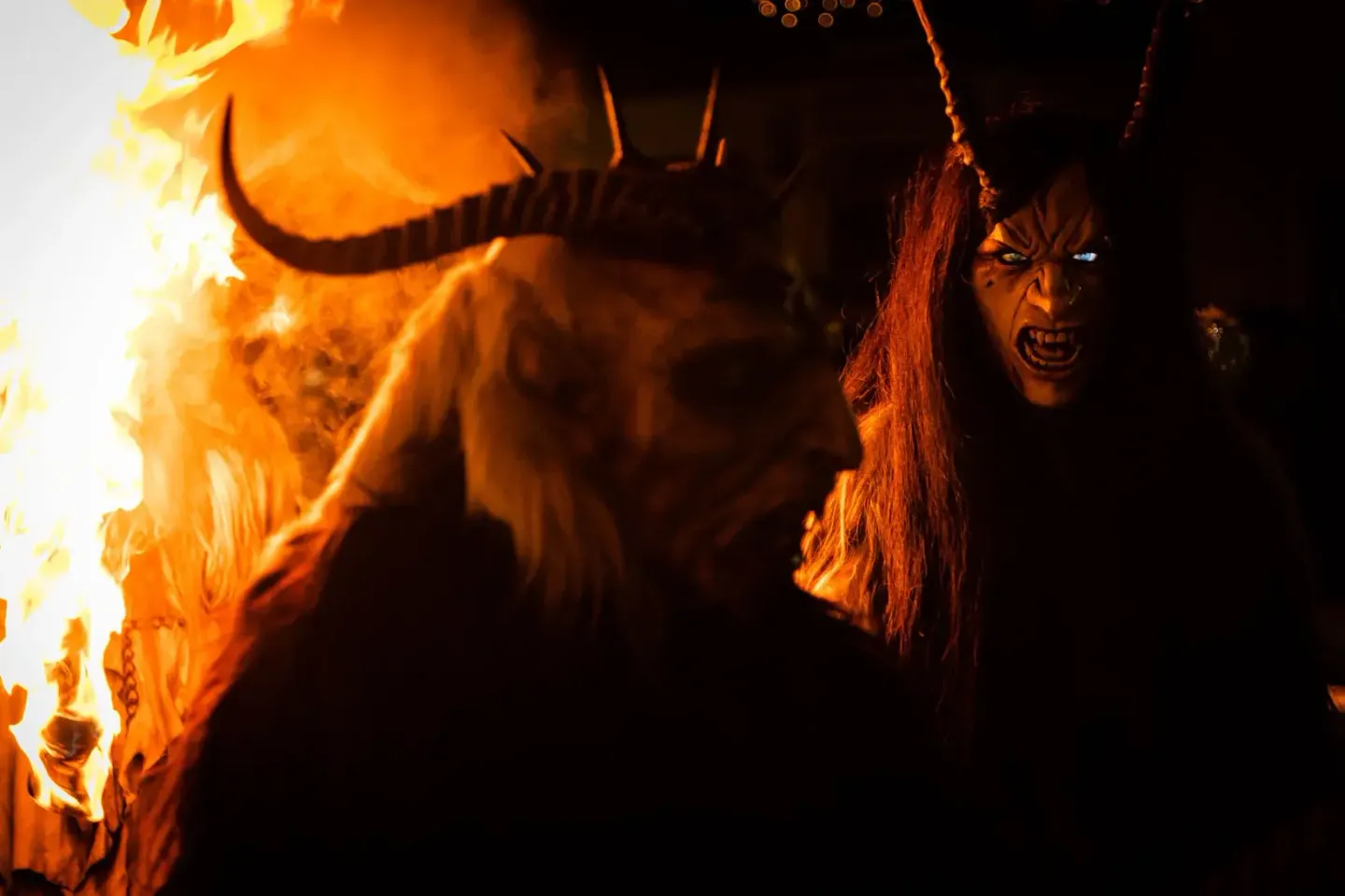 Krampus-Figur mit Hörnern und langen Haaren im Feuerglanz bei einer Eventfotografie in Wien