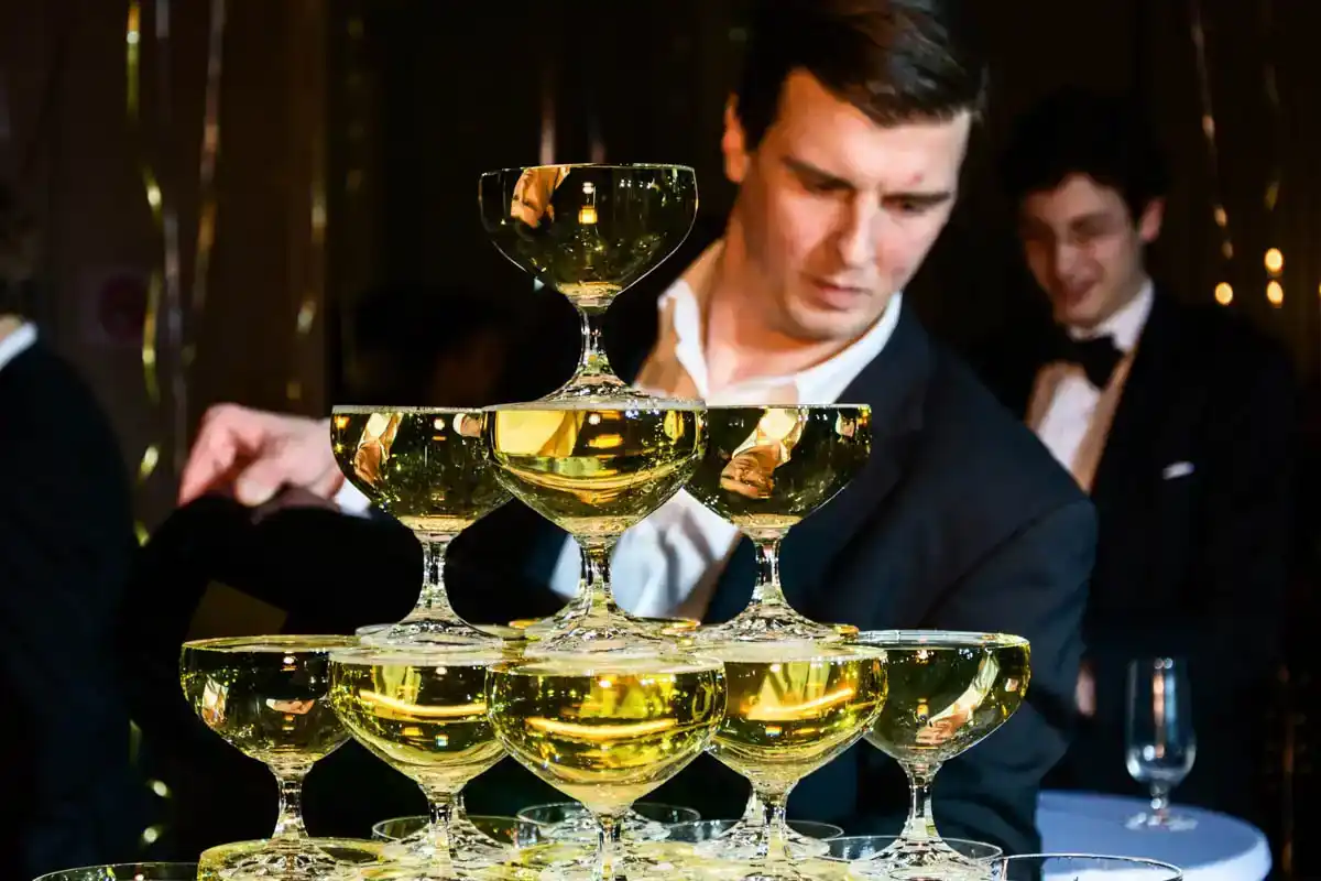 Elegante Champagnerpyramide bei Firmenevent Wien mit Mann in Smoking, der Gläser arrangiert
