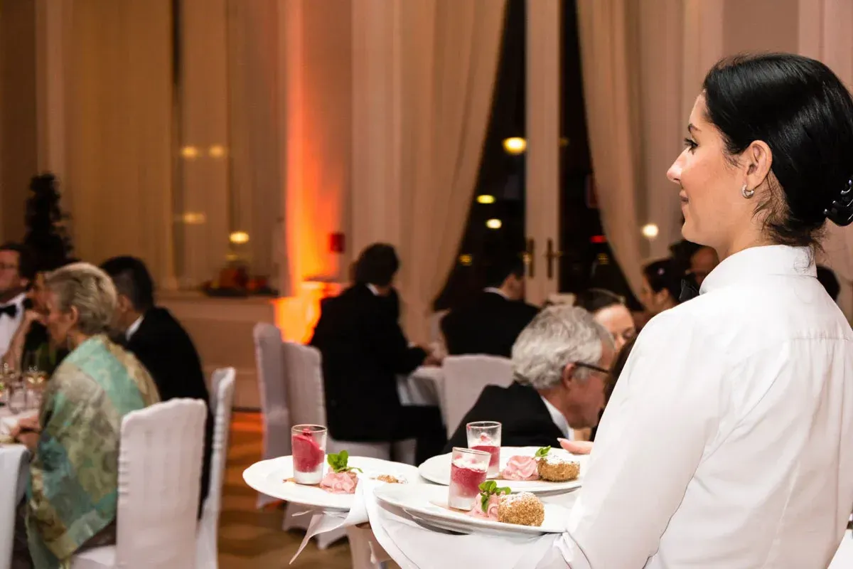 Serviererin in weißer Bluse bei Firmenevent im eleganten Kursalon Wien mit Gästen und festlicher Beleuchtung