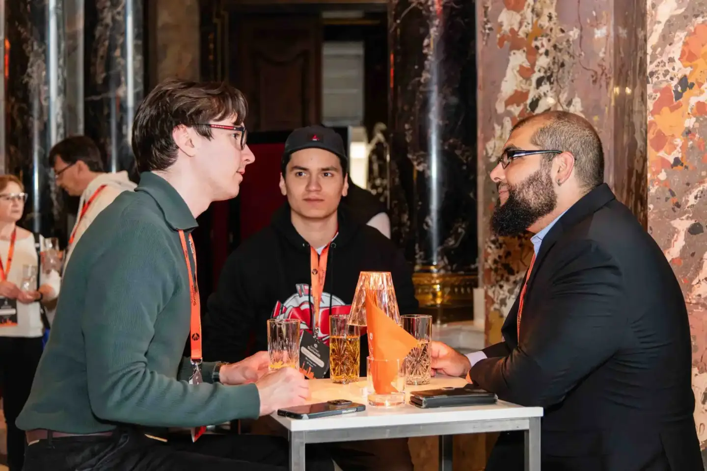 Drei Personen im Gespräch bei einem Firmenevent Wien, Netzwerking mit Getränken an einem Stehtisch