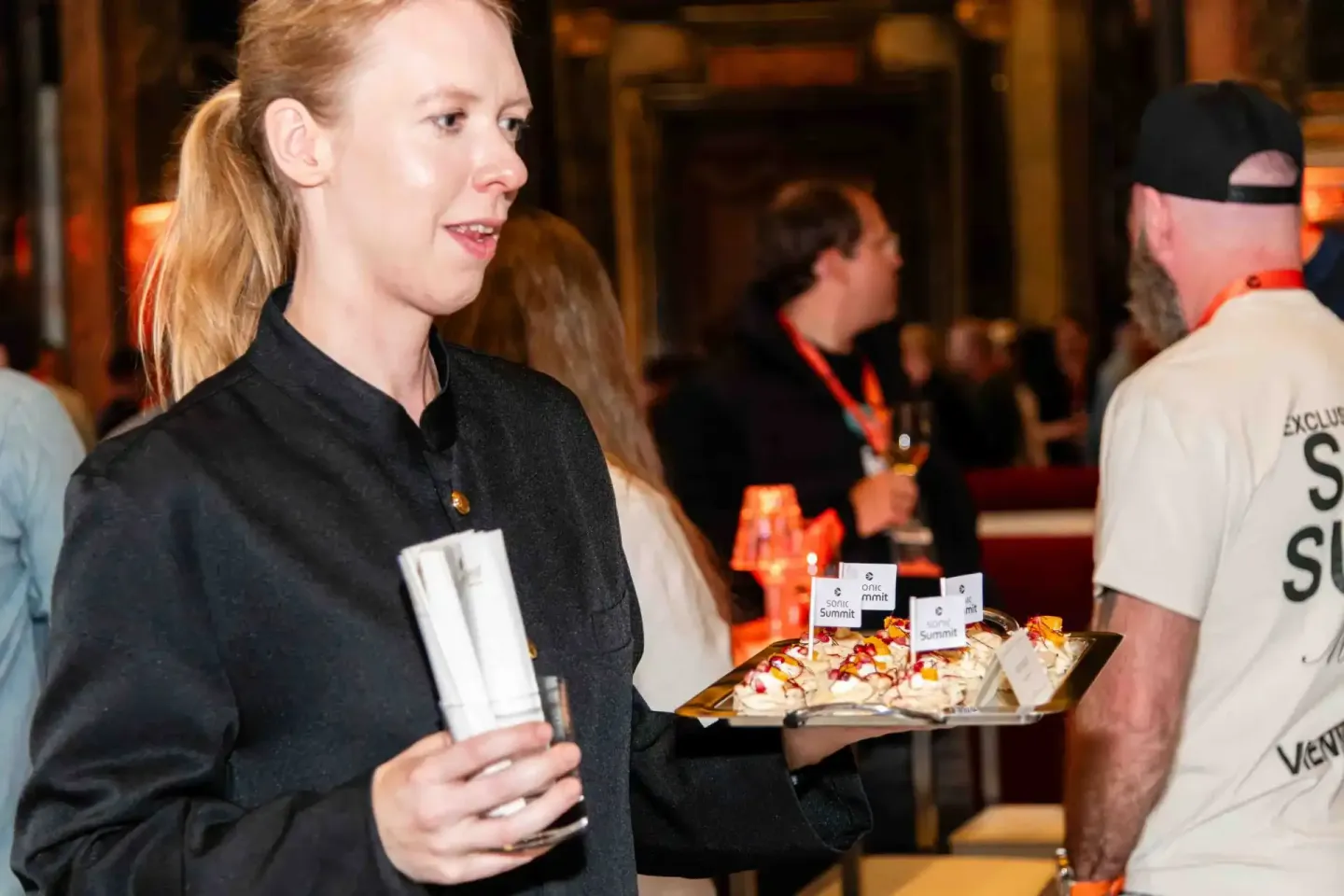 Frau mit rötlichem Haar präsentiert Häppchen auf Tablett beim Sonic Summit Event - Eventfotografie Wien