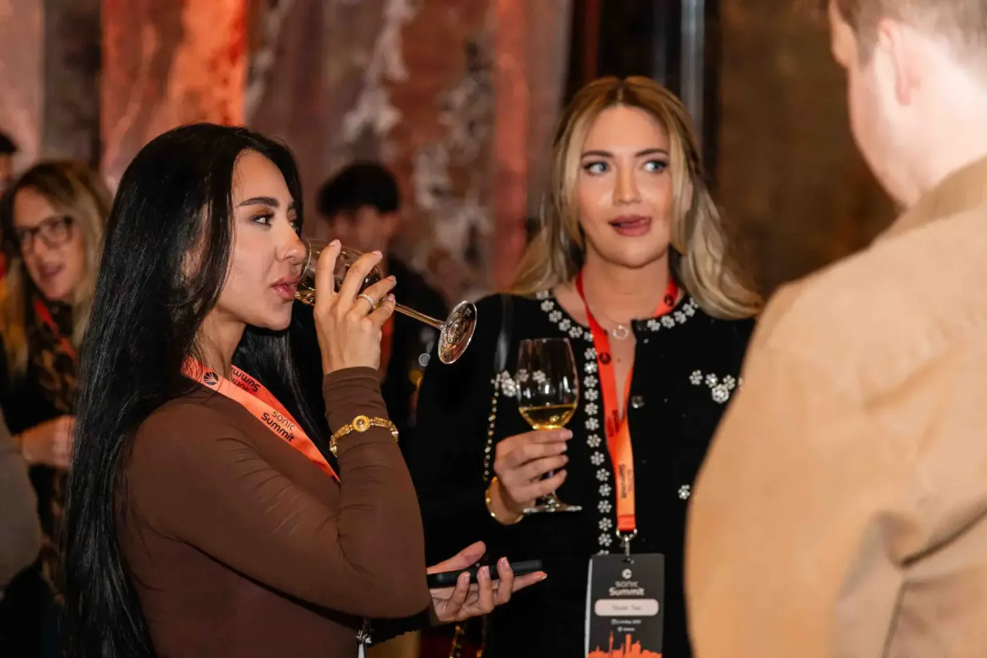 Zwei Frauen beim Networking auf dem Sonic Summit in Wien, eine trinkt Wein während sie sich unterhalten - professionelle Even