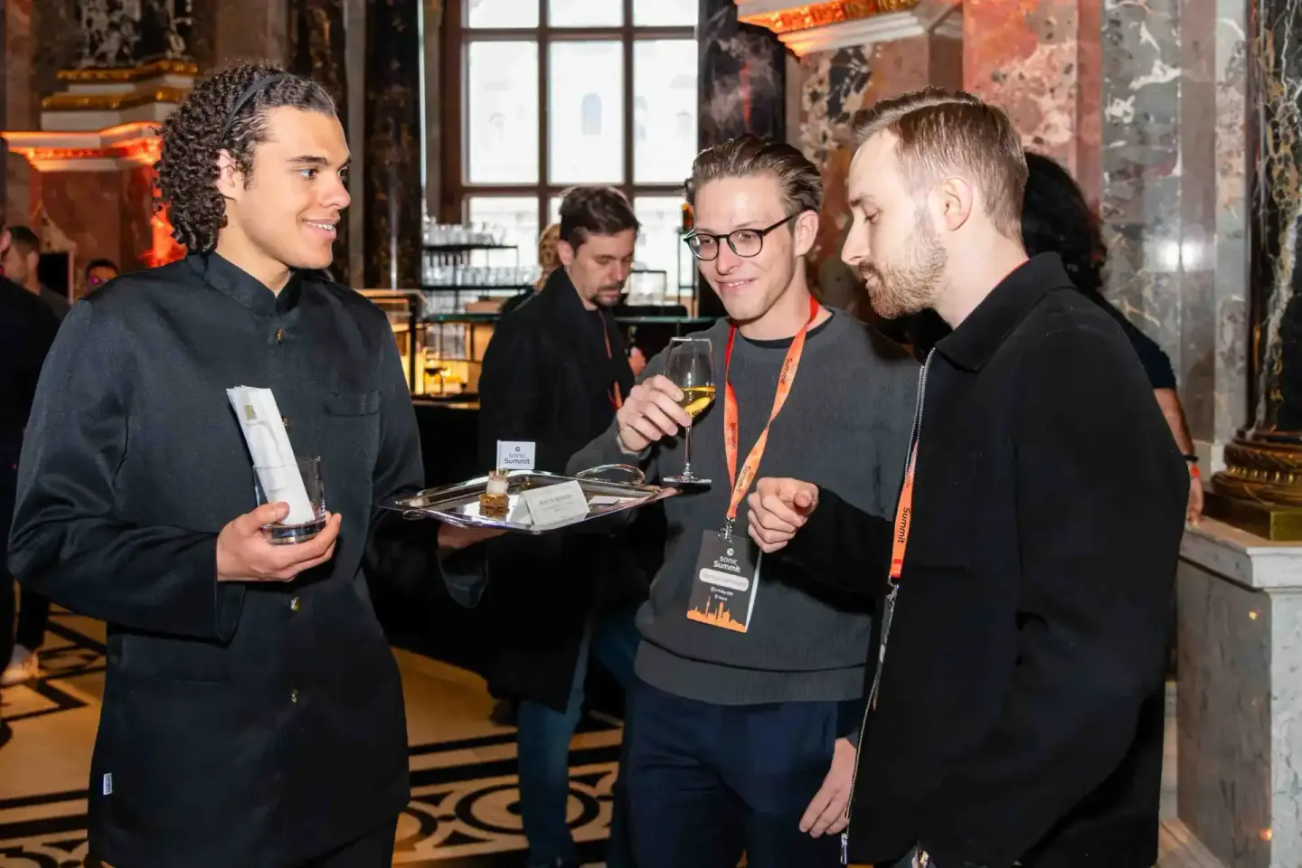 Vier Männer in schwarzer Kleidung mit Namensschildern unterhalten sich beim Sonic Summit Event – Eventfotografie Wien