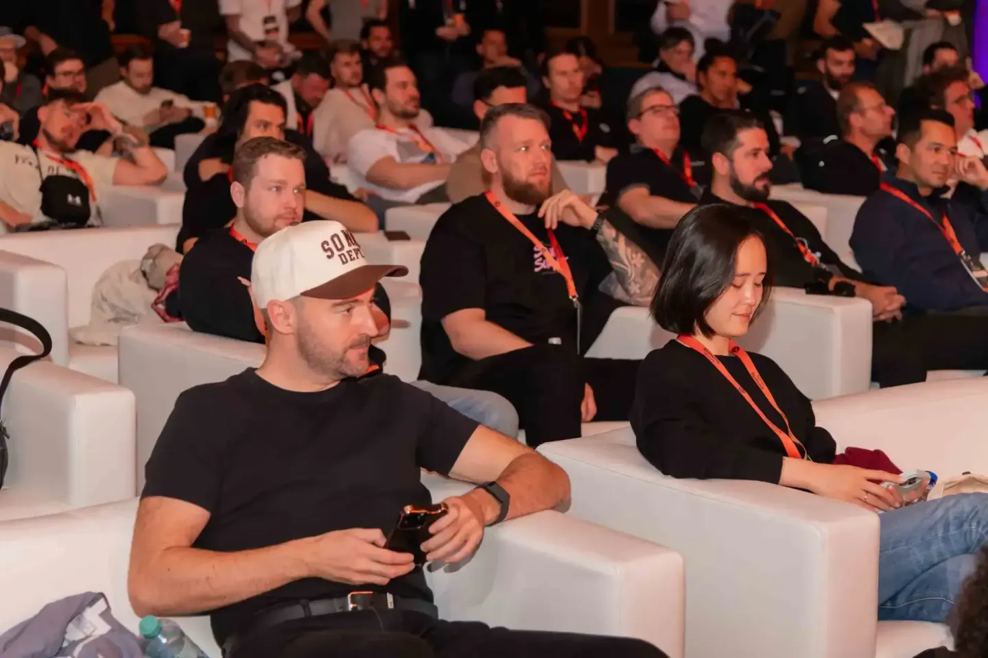 Teilnehmer beim Sonic Summit Event sitzen in weißen Sesseln und verfolgen die Veranstaltung - professionelle Eventfotografie 