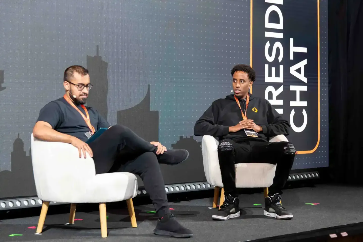 Zwei Sprecher auf der Sonic Summit im Dialog auf weißen Sesseln vor Bühnenhintergrund, Eventfotografie Wien