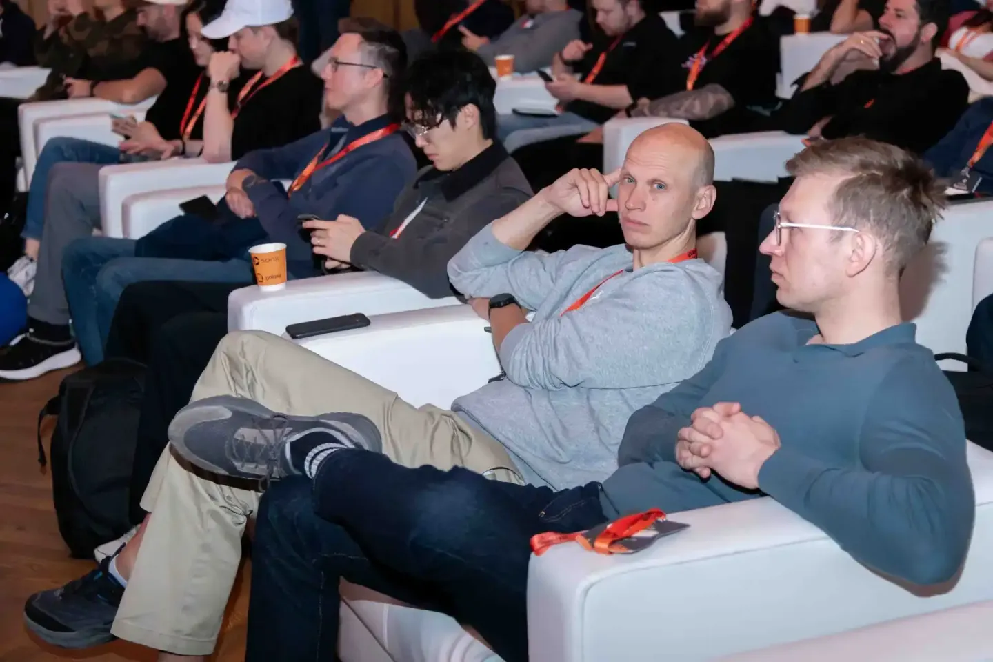 Teilnehmer beim Sonic Summit sitzen in Reihen und verfolgen aufmerksam eine Präsentation - professionelle Eventfotografie Wie