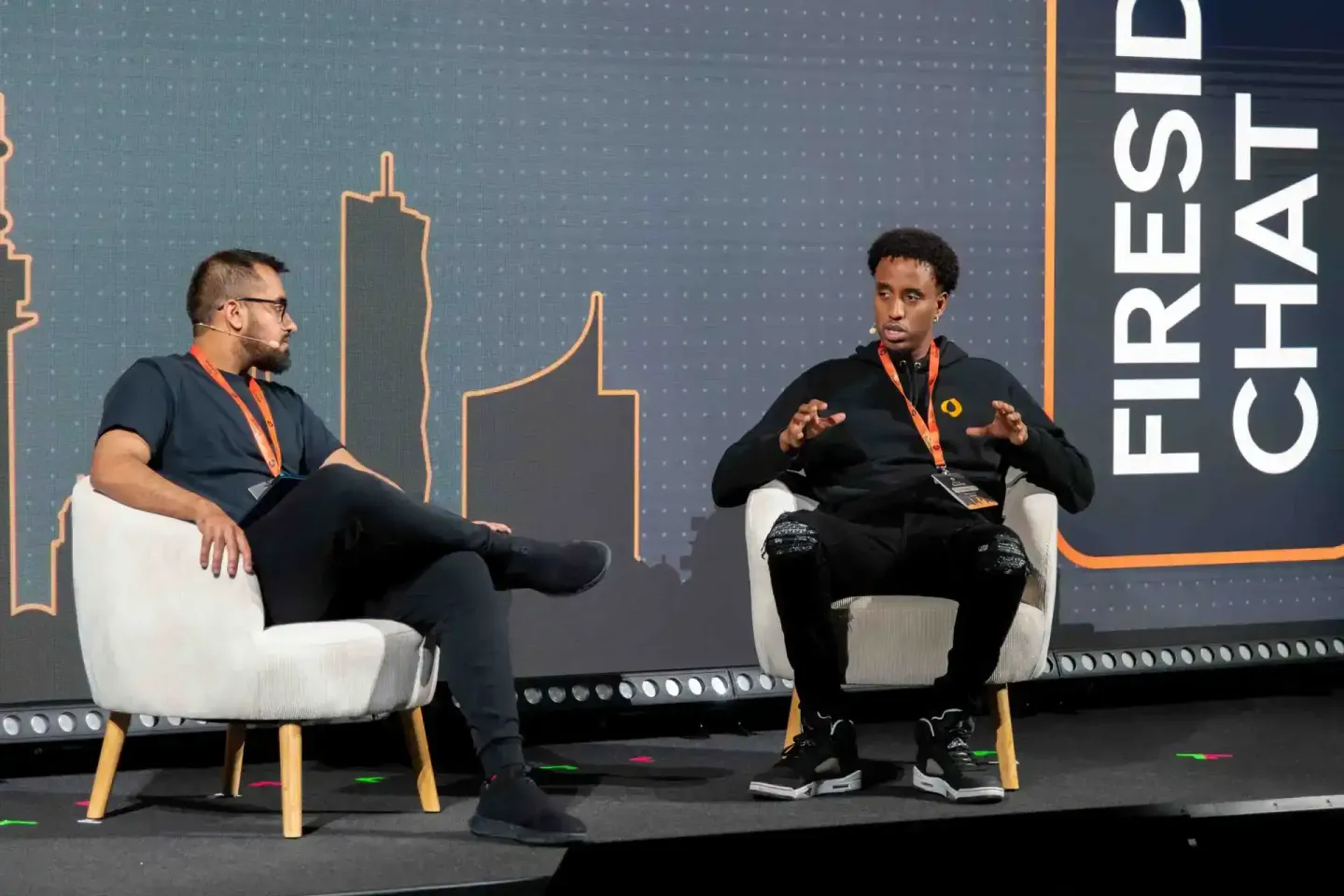 Zwei Sprecher bei einer Podiumsdiskussion auf der Sonic Summit in Wien, beide tragen Lanyards und sitzen auf weißen Sesseln v