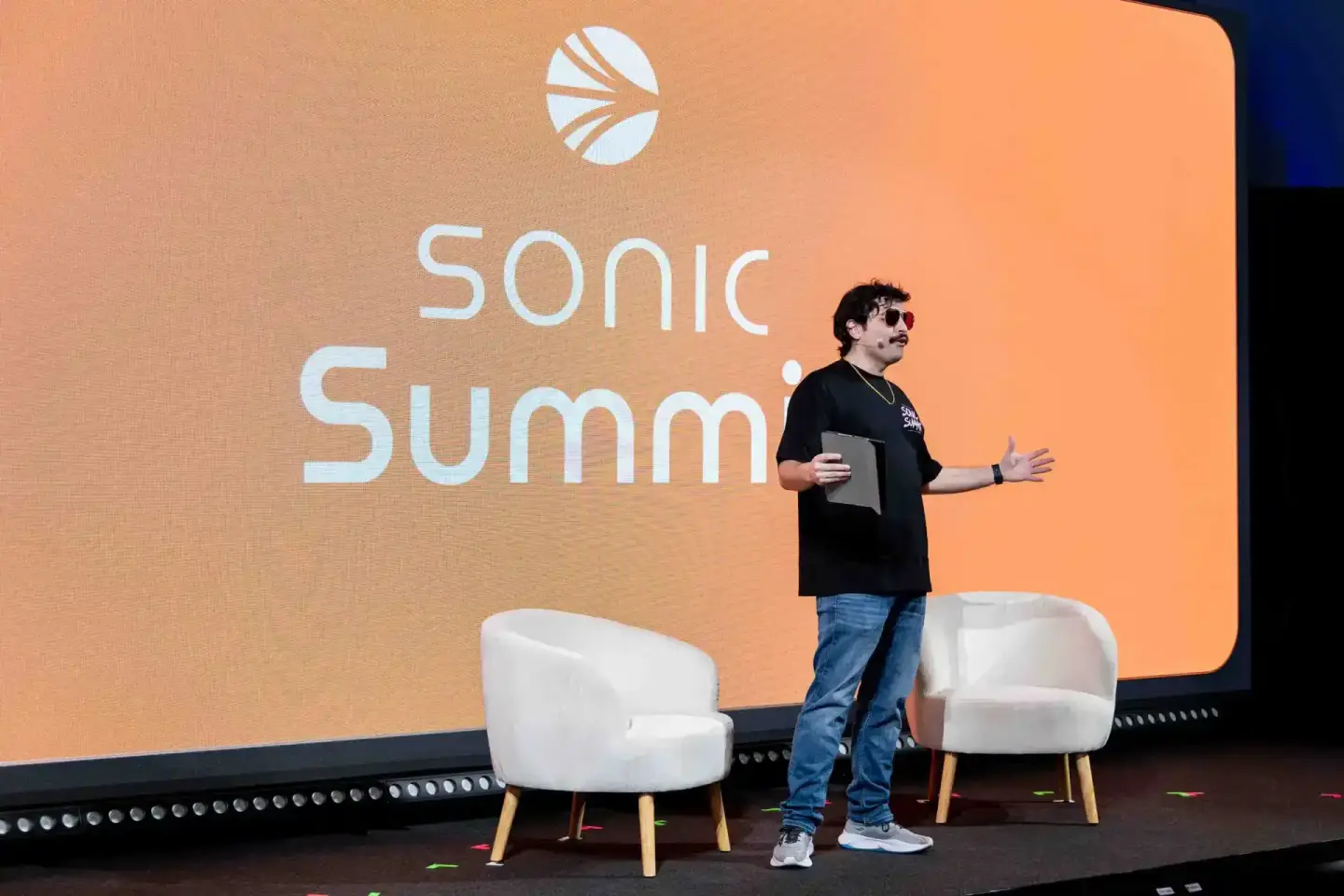 Speaker präsentiert auf der Sonic Summit auf einer schwarzen Bühne mit orangem Hintergrund – professionelle Eventfotografie W