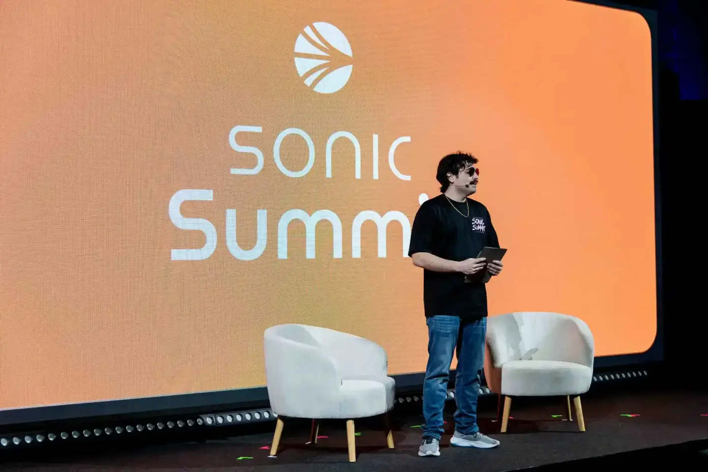 Sprecher auf der Sonic Summit Bühne vor orangegelbem Hintergrund – Eventfotografie Wien