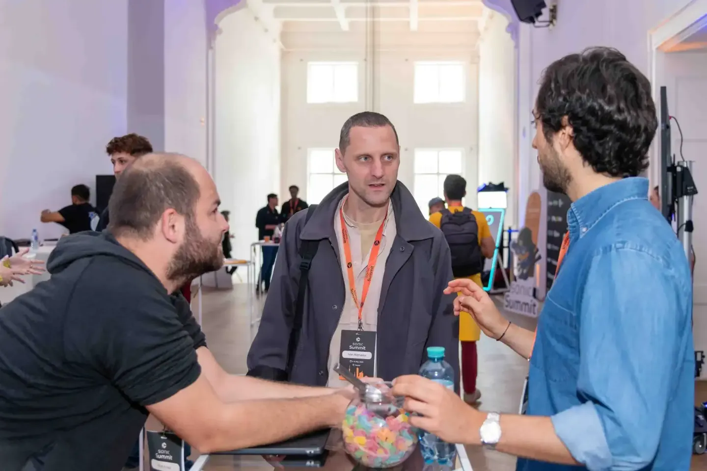 Drei Männer im Gespräch auf dem Sonic Summit Event in Wien, einer trägt ein orange Besucher-Badge, Eventfotografie dokumentie