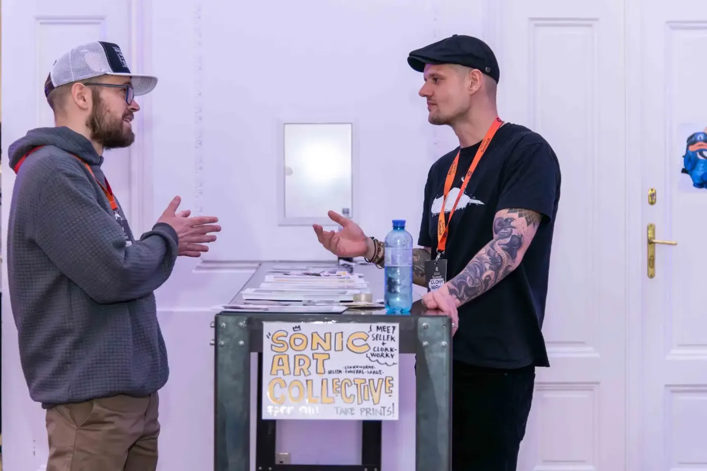 Zwei Männer im Gespräch an einem Tisch mit 'Sonic Art Collective' Schild bei einem Eventfotograf-Einsatz in Wien