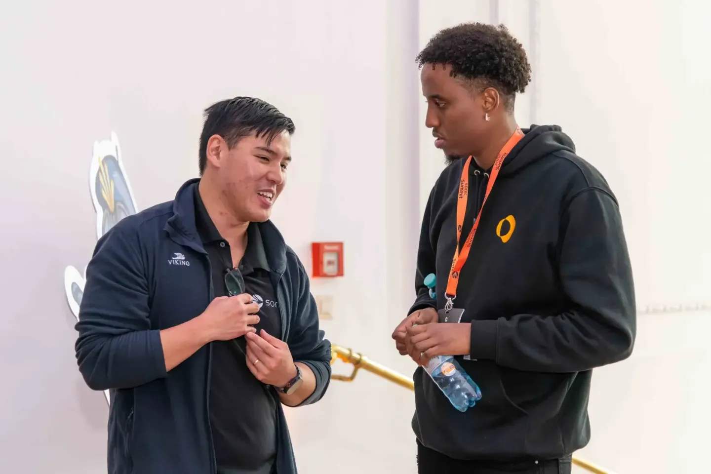 Zwei junge Menschen im Gespräch bei einem Firmenevent Wien, einer trägt ein Viking-Polo-Shirt, der andere ein schwarzes Hoodi