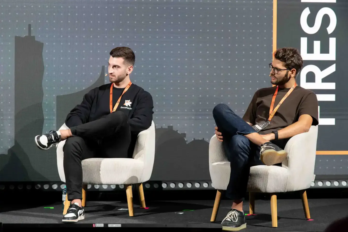 Zwei Redner sitzen auf der Bühne des Sonic Summit Events in Wien und diskutieren während einer Podiumsdiskussion