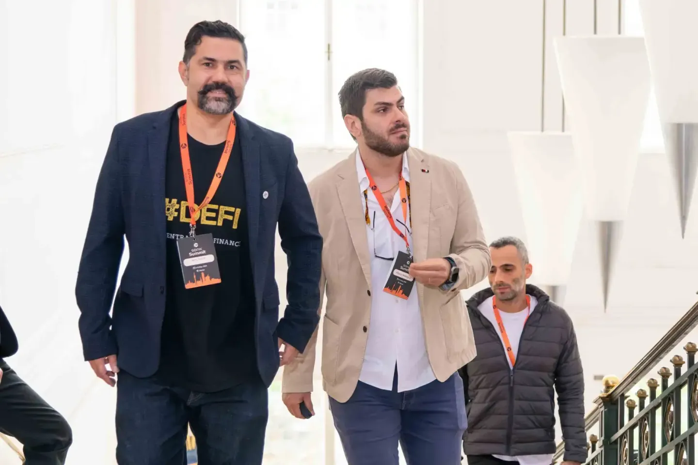 Drei Männer mit Konferenz-Badges auf einer Treppe bei einer Veranstaltung, Eventfotografie Wien