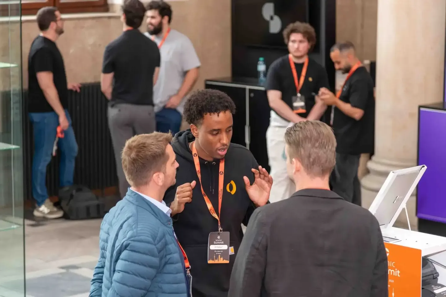 Eventfotograf dokumentiert intensive Diskussion zwischen drei Teilnehmern beim Sonic Summit in Wien mit Badge und Laptop im H