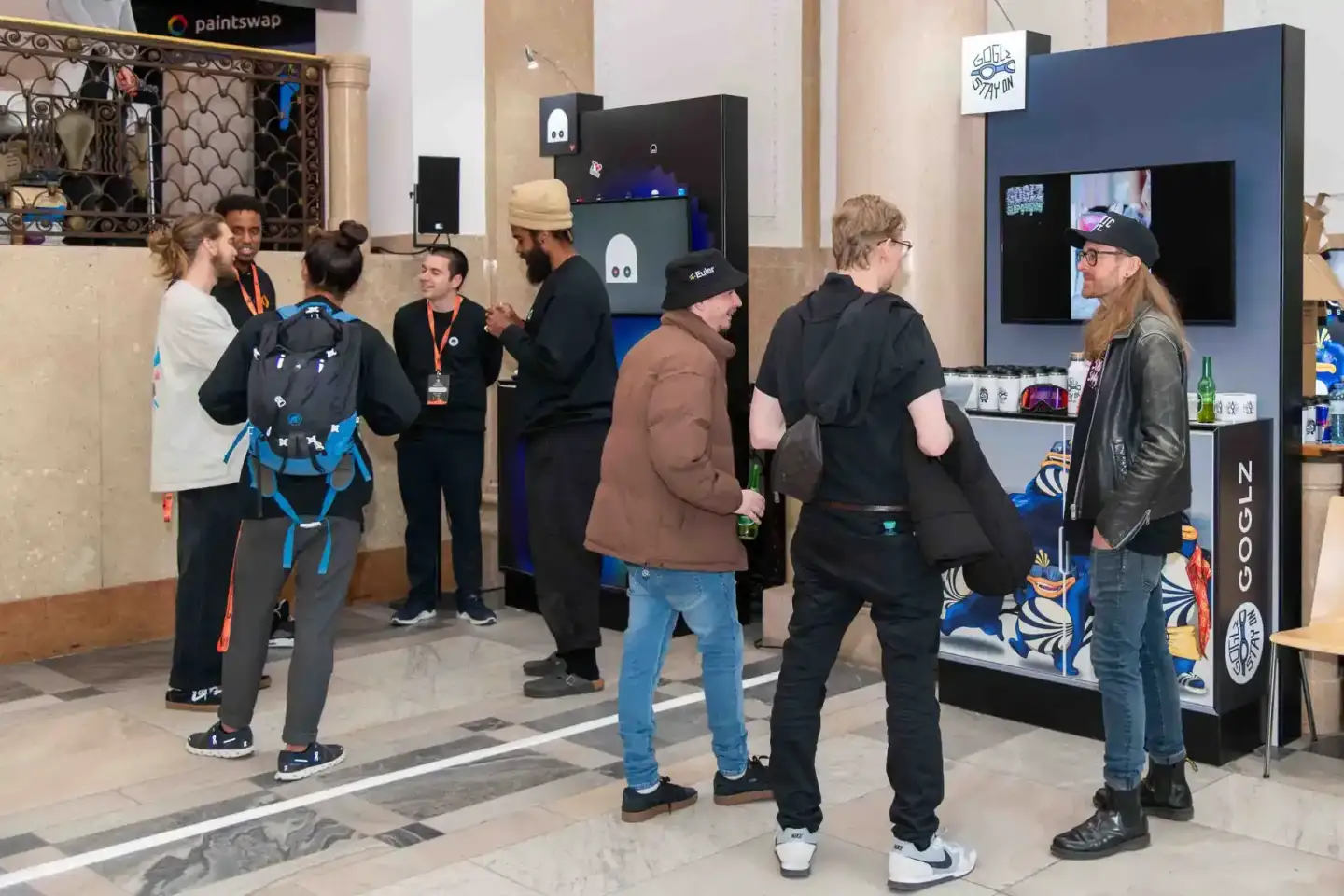 Besucher beim Sonic Summit Event in Wien unterhalten sich an einem Messestand mit Produkten und Displays