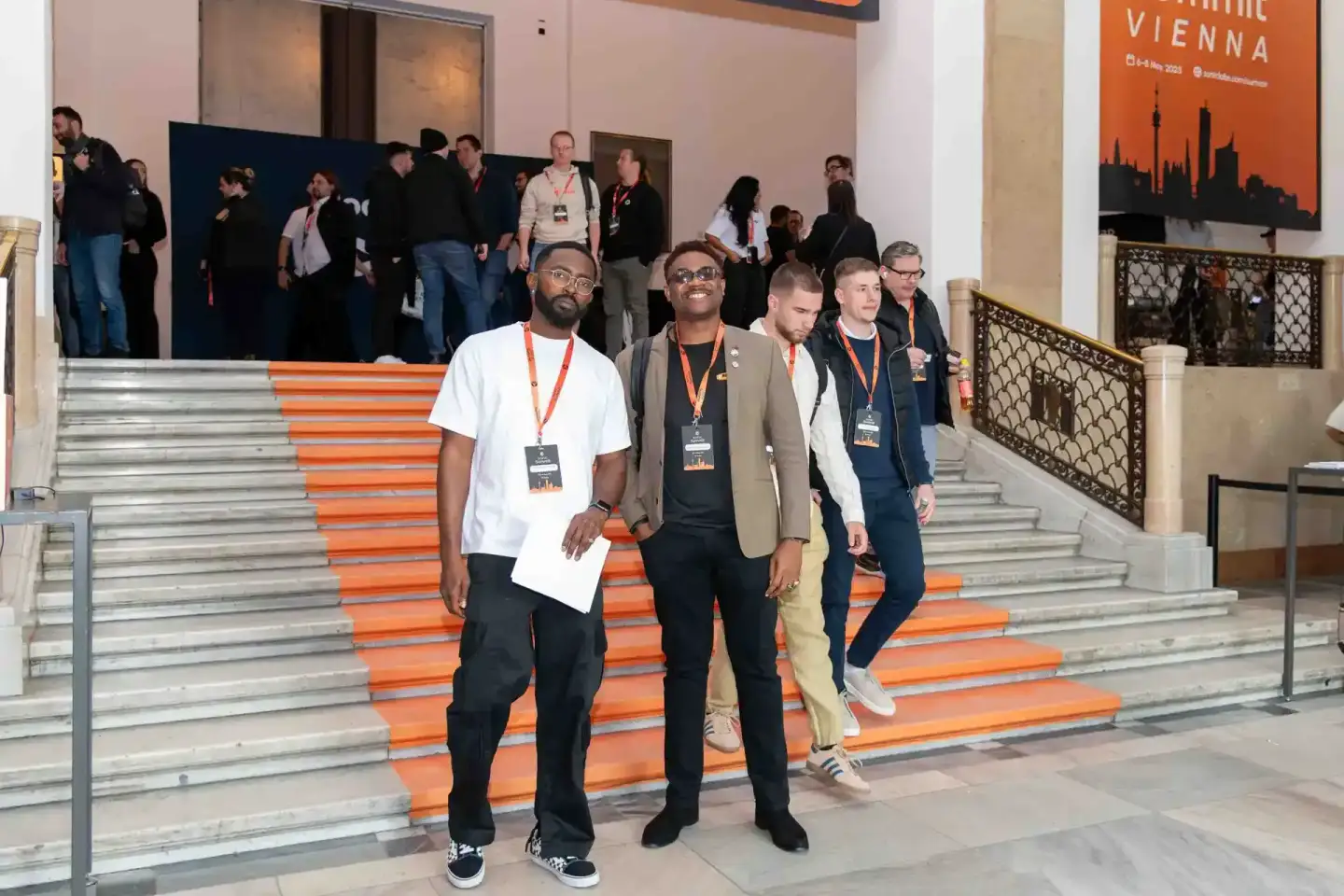 Vier Teilnehmer mit Badges auf orangenen Treppen beim Sonic Summit Event – professionelle Eventfotografie Wien