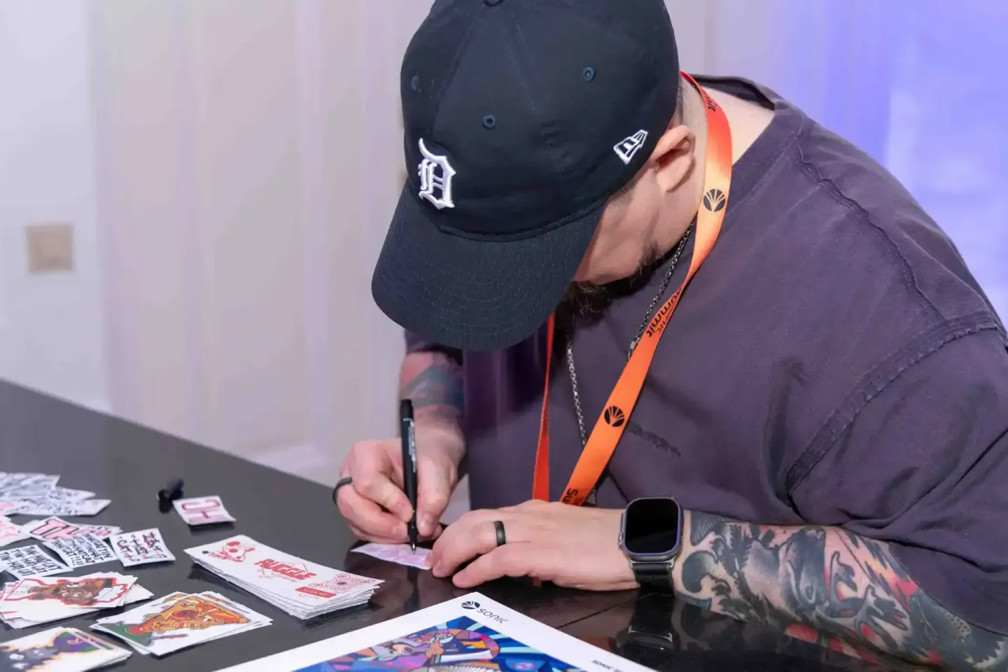 Eventfotograf dokumentiert Autogrammstunde auf dem Sonic Summit: Mann mit Detroit-Cap signiert Merchandise für Fans