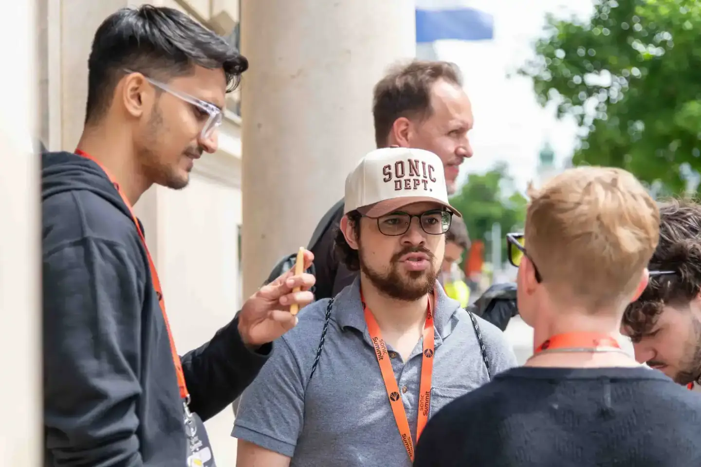 Eventfotograf dokumentiert Diskussion zwischen mehreren Teilnehmern beim Sonic Summit in Wien mit Lanyards und Cap