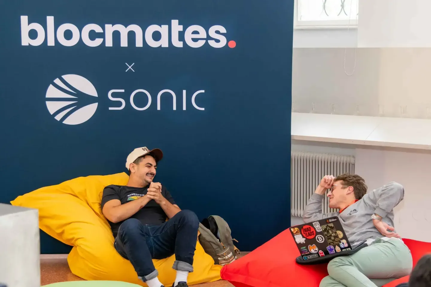 Zwei Personen sitzen entspannt vor der Blocmates x Sonic Wand bei einem Firmenevent Wien und unterhalten sich lachend
