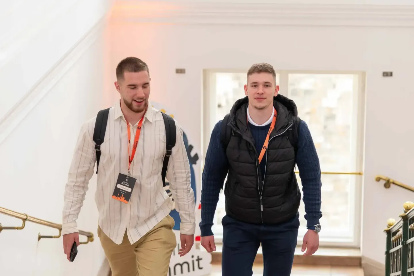 Zwei junge Männer mit Badges gehen durch einen modernen Flur – Eventfotografie Wien bei der Sonic Summit Konferenz