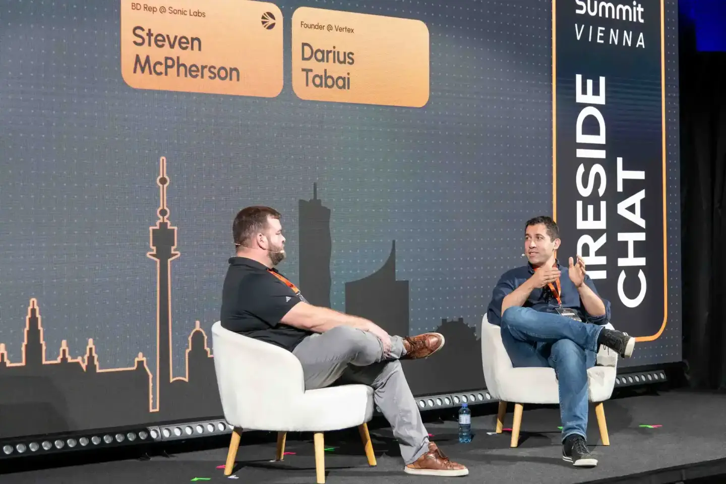 Zwei Sprecher auf dem Sonic Summit Vienna 2024 im Dialog - Steven McPherson und Darius Tabai sitzen sich in weißen Sesseln ge