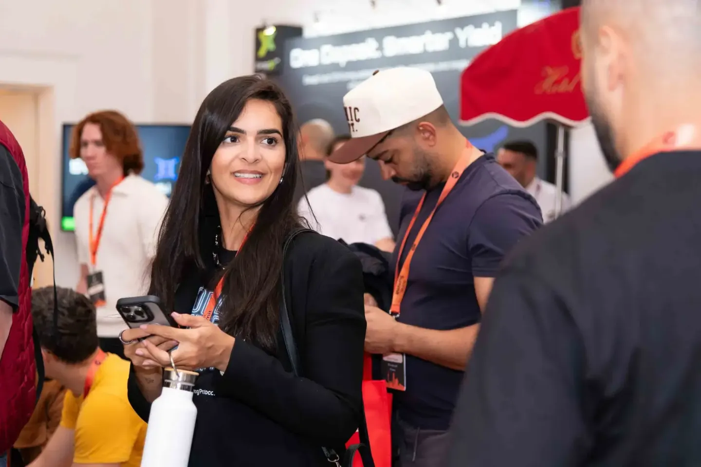 Eventfotografie Wien: Besucher beim Sonic Summit networken mit Smartphones und Lanyards in modernem Veranstaltungsraum