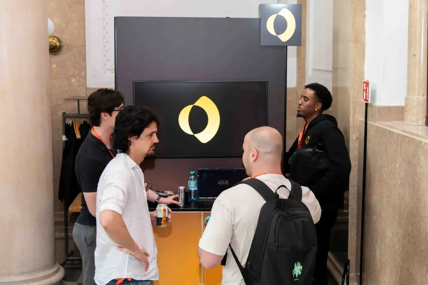 Eventfotograf dokumentiert Diskussionsrunde beim Sonic Summit: Vier Teilnehmer stehen vor großem Display mit gelbem O-Logo in